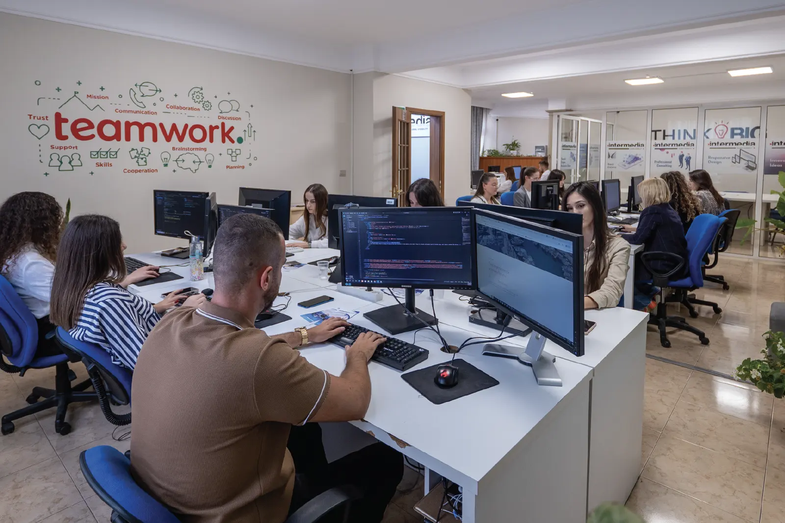 Zyra e hapur e InterMedia me murin “Teamwork” dhe ekipin në punë